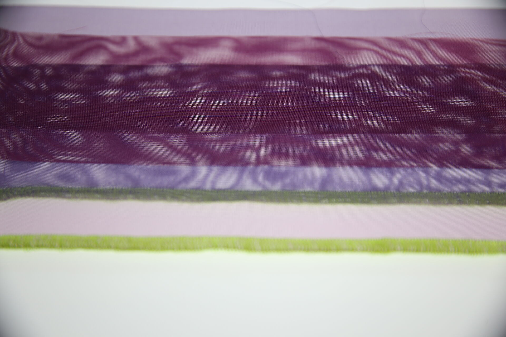 violette Stoffe mit neongrüner Kante im Gegenlicht