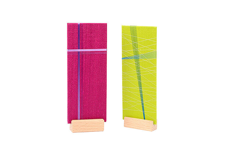 farbige Seidenflächen mit bunten Garnen umwickelt zwei FadenKreuze in Pink und grün