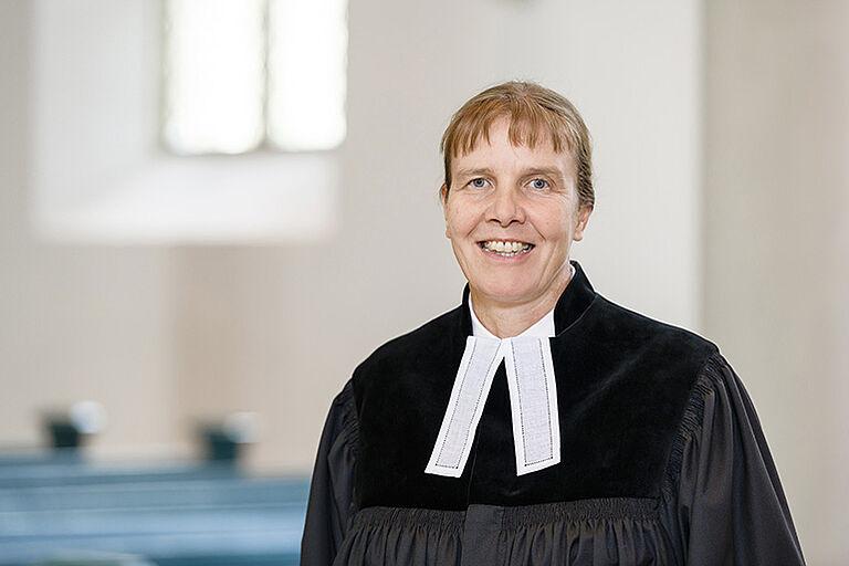 eine evangelische Pfarrerin trägt den Talar mit Beffchen Pfarrerin mit Talar und Beffchen