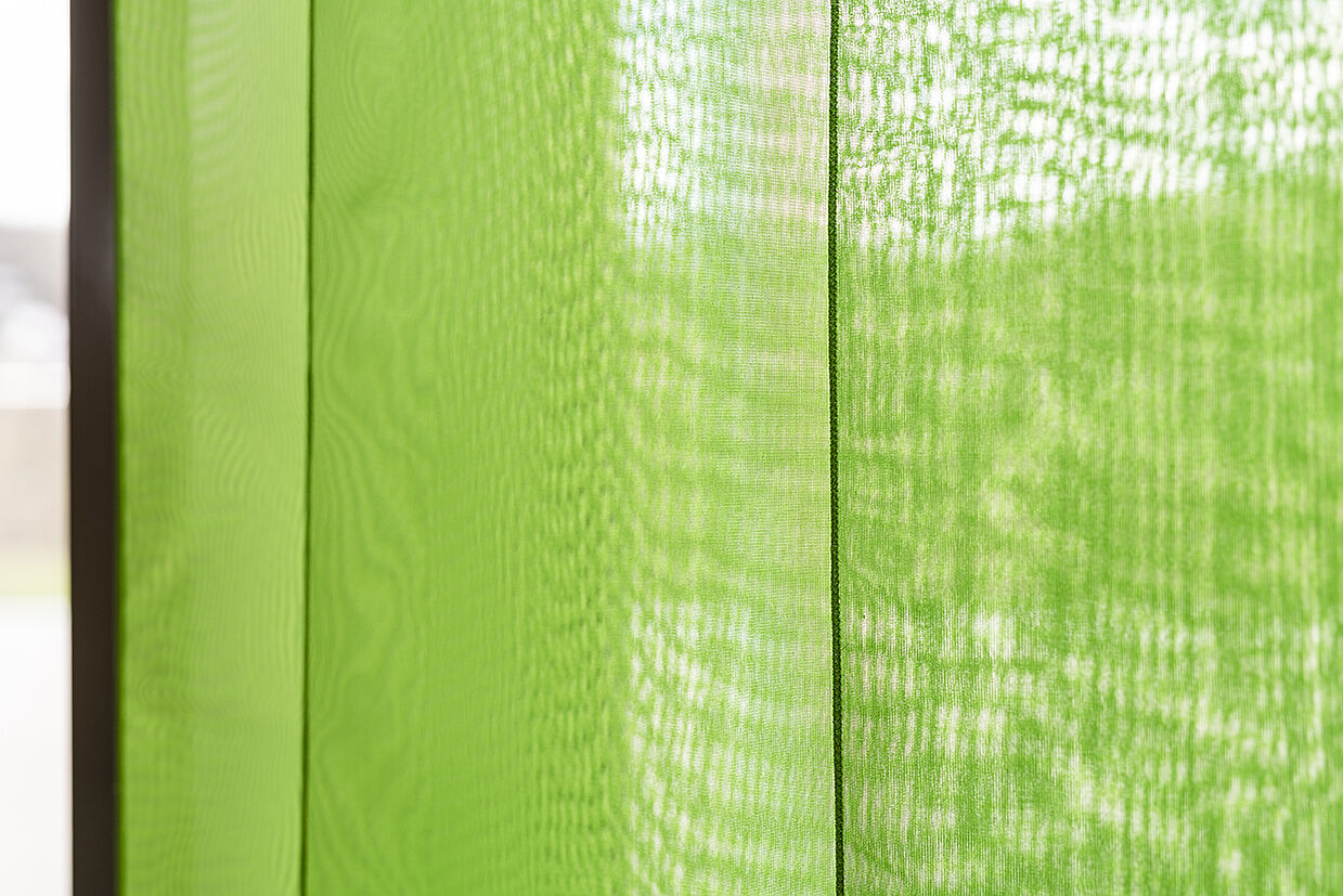 Blick auf Grün durch Grün hindurch grünes Parament im Detail mit Durchblick auf Landschaft