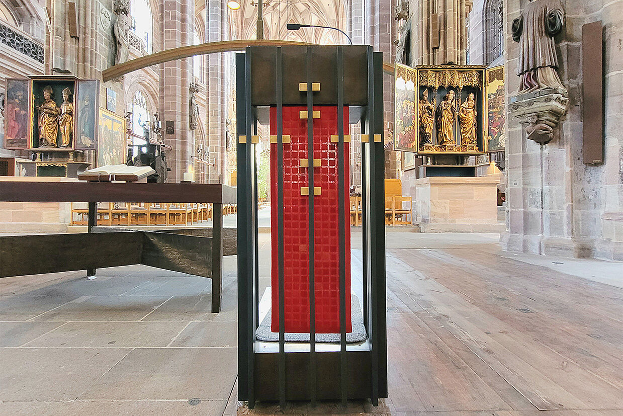 In der Lorenzkirche steht ein modernes Pult mit goldenen Quadraten, daran hängt ein rotes Parament